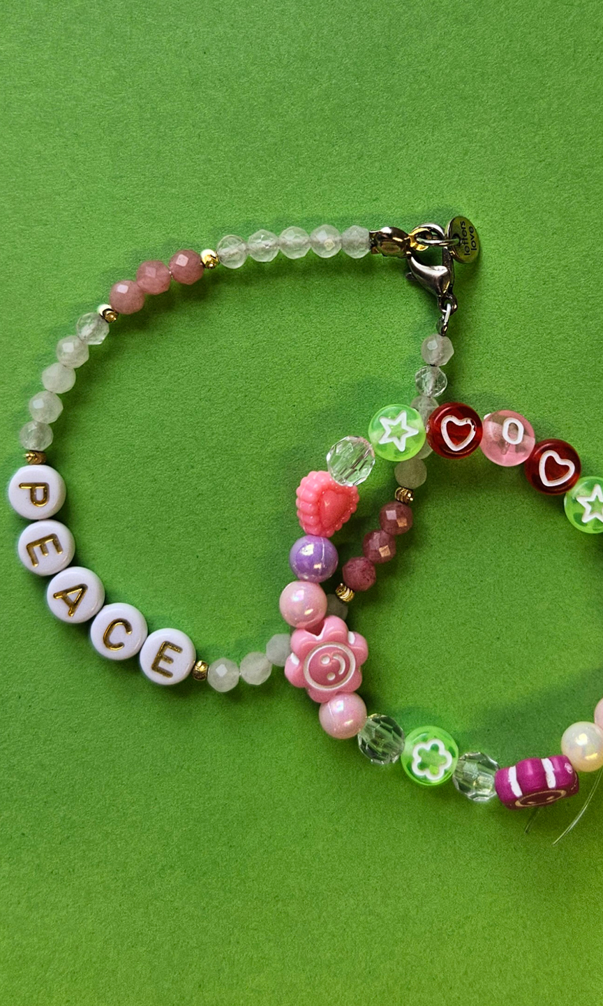 Armbänder aus aufgereiten Perlen liegen auf einem grünen Grund.