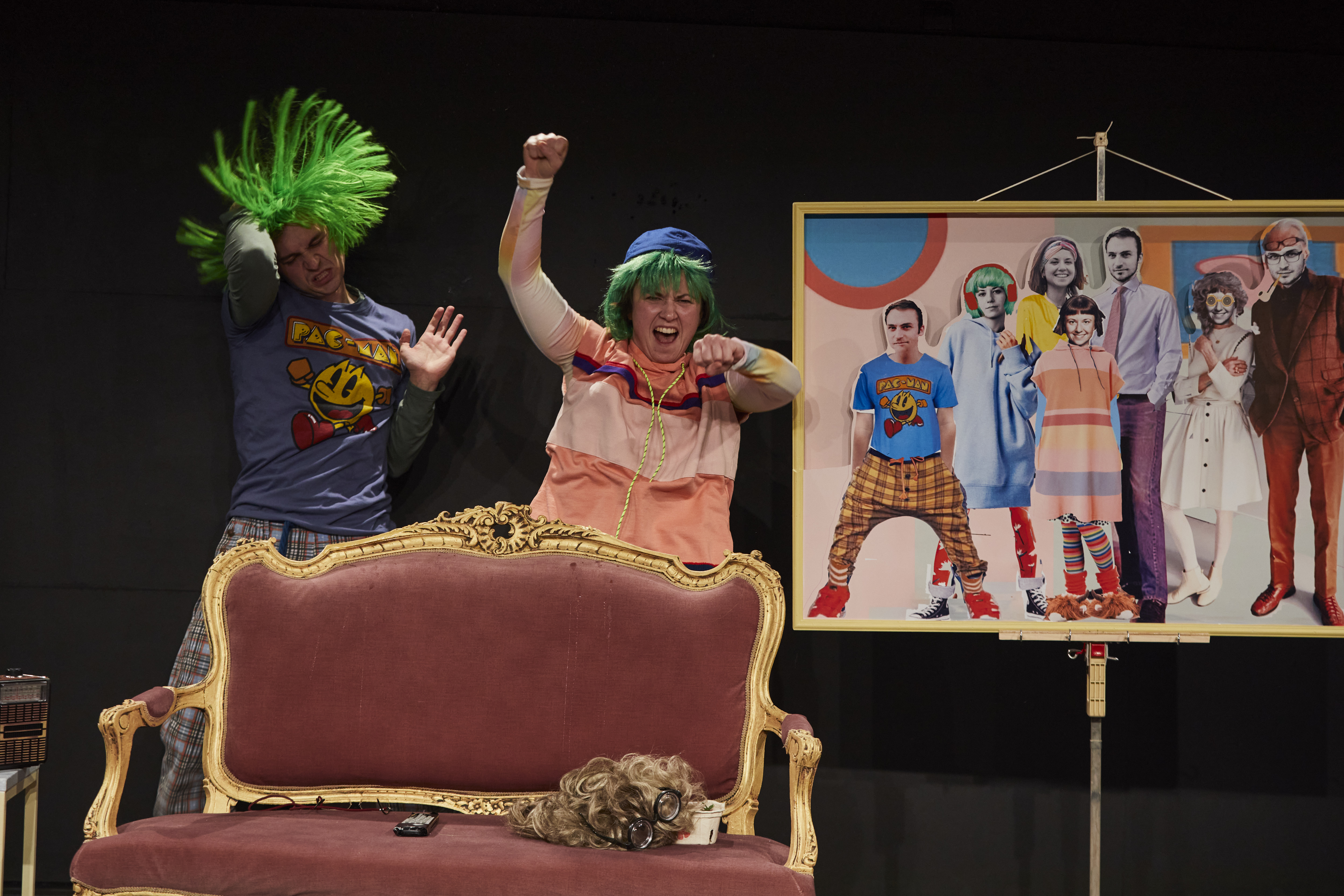 Punk mit grünen Haaren tanzt mit Oma hinter einem Sofa