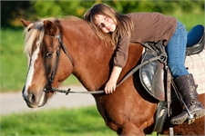 Mädchen auf Pferd das sich an den hals des Tieres schmigt